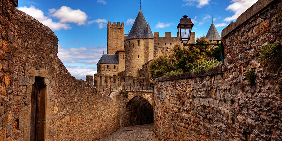 Carcassonne is a historic french castle, a stone archway and turrets can be seen.   